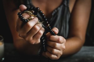 Une femme tient un chapelet ou collier de prière