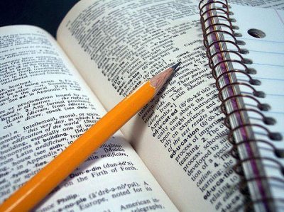 Un crayon à papier posé sur un dictionnaire avec un cahier pour prendre des notes, matériel pour étudier.