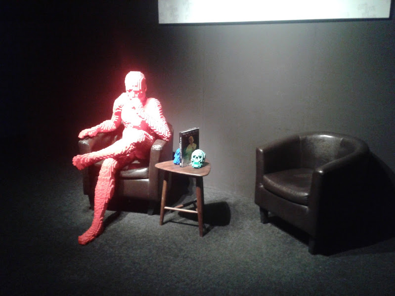 Think de Nathan Sawaya, un homme en Lego est assis sur un fauteuil en pleine réflexion.