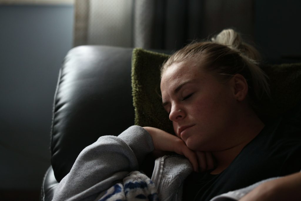 Symptôme de la phase down : une grosse fatigue. Une femme dort sur son canapé