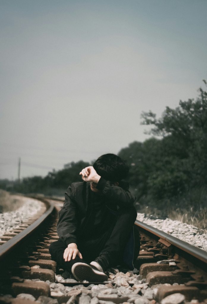 Une personne est assise sur un rail de chemin de fer.