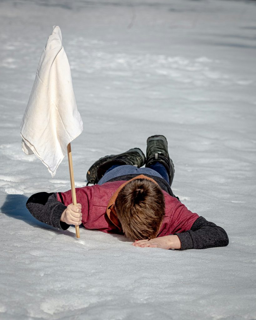 Chasser le naturel ou abandonner toute velléité de changement, personne allongée sur la neige avec un drapeau blanc