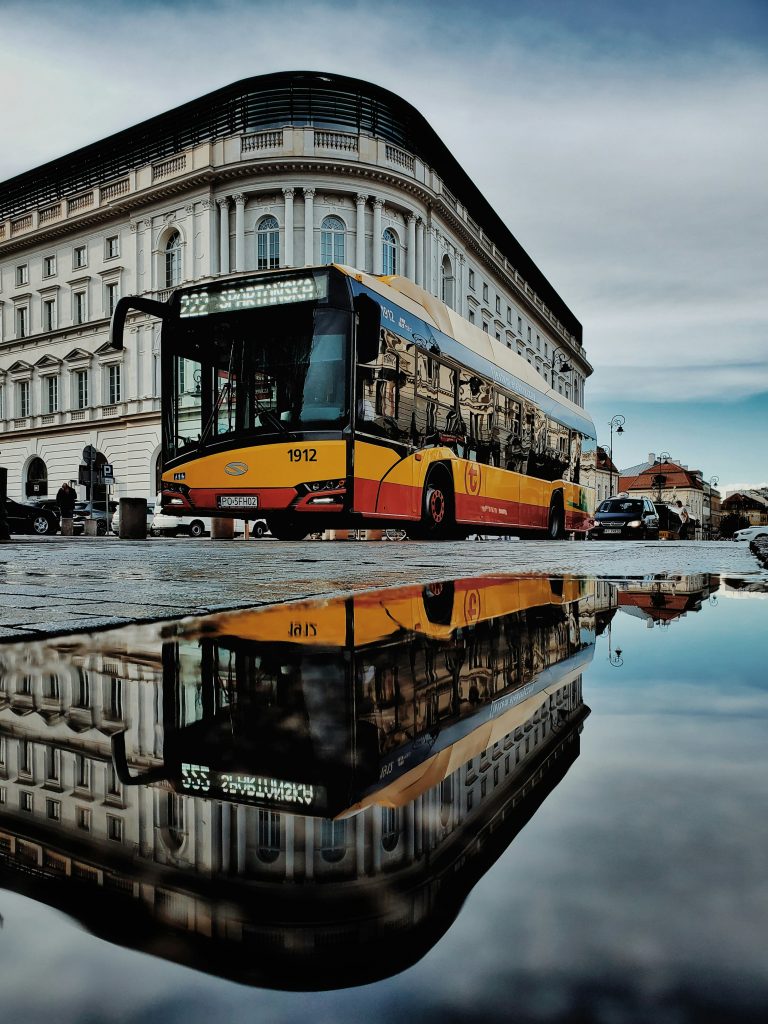 Un bus traverse la ville, reflet dans une flaque